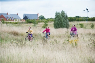 Family cycling near houses and wind turbine