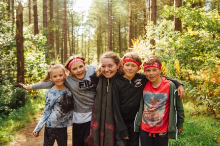Five children, faces painted, in woodland 