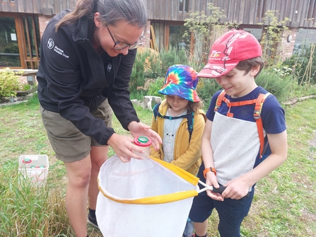 Emily from DWT showing bug finder to two children holding sweep net