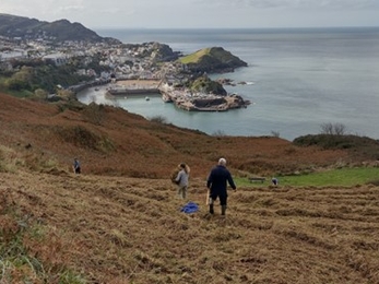 Two people walking up a coastal hill.
