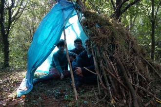 Children sitting in their forest school shelter