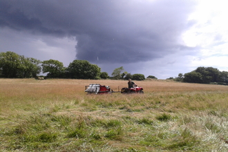 Quad bike pulls a seed harvester across a field