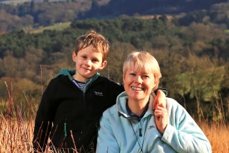 Kati and her son sat in a field with woods in background