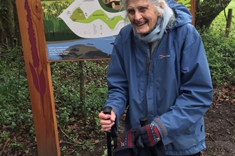 Woman stands in front of nature reserve sign