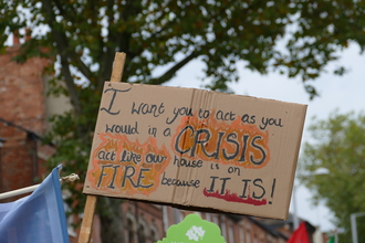 A poster at a climate march reads: "I want you to act as you would in a crisis. Act like our house is on fire because it is!"