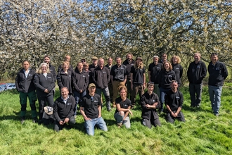 DWT staff in black shirts and jumpers grouped together in front of tree with blossom