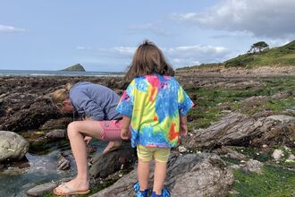 Toddler rockpooling with a parent