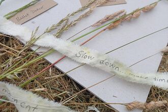 paper on the grass with vegetation on it and ribbon with calming statements such as "slow down"