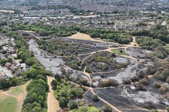 aerial shot of Mincinglake Valley Park, this hills blackened with ash and the line of footpaths carving through, with the houses close to the boundaries