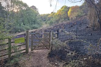 the gate for the reserve, burnt with the charred hillside behind