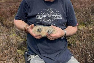 David kneeling whilst holding who young birds