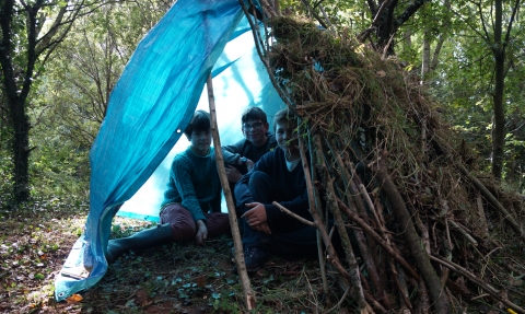 Children sitting in their forest school shelter