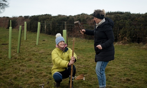 Two women making holes to plant trees