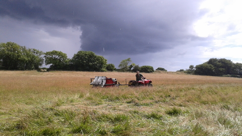 Quad bike pulls a seed harvester across a field