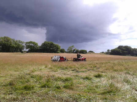 Quad bike pulls a seed harvester across a field