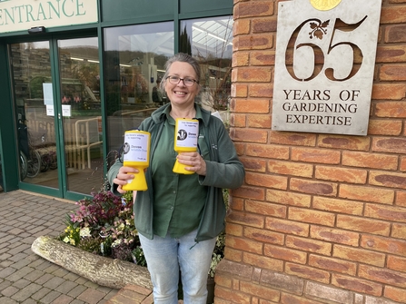 Person holding donation tins outside of garden store