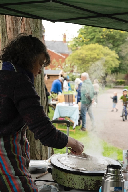A woman cooking galettes under a gazebo in a garden