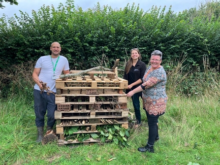 Emily NDN Officer and two residents from Grandisson Court standing next to a large bug hotel made of old wooden pallets
