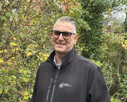 Simon smiling at the camera on an autumn day