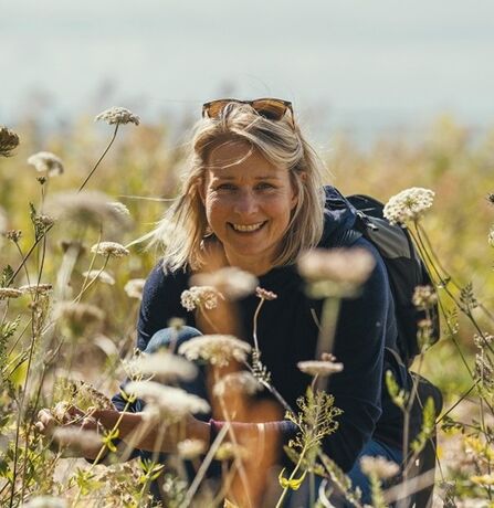 Victoria smiling at the camera whilst immersed in a wildflower meadow