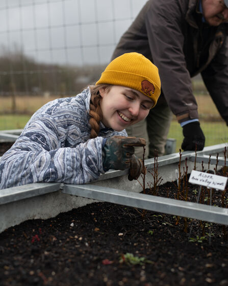 Flo smiling and tending to her tree saplings