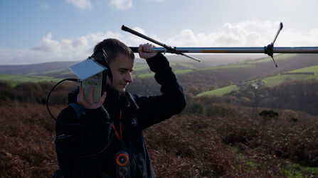 Young Jack Standing on top of hill on Exmoor Radio Tracking with receiver close to his ear