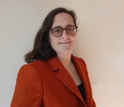Head and shoulder shot of Wendy smiling at the camera in a red blazer