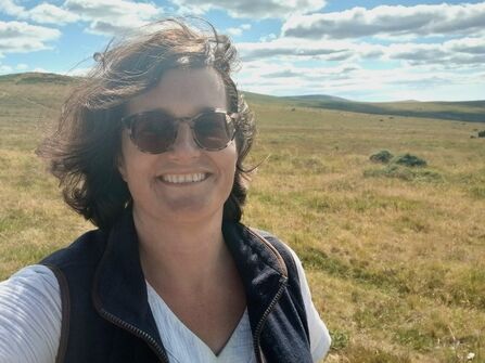 Wendy smiling in a selfie with rolling grass fields behind.