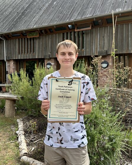Jack smiling whilst proudly holding is Traineeship Certificate