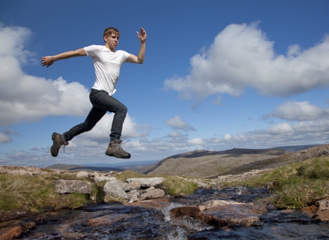 Boy jumping over a river